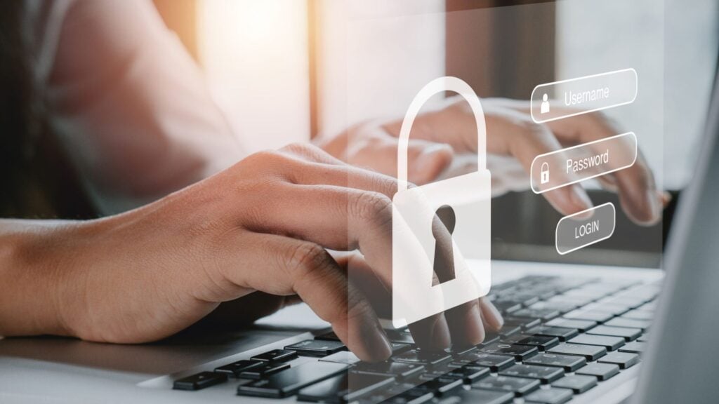 Hands typing on a laptop keyboard with a holographic lock icon and login fields visible, representing cybersecurity or secure login through a Conditional Access System (CAS).