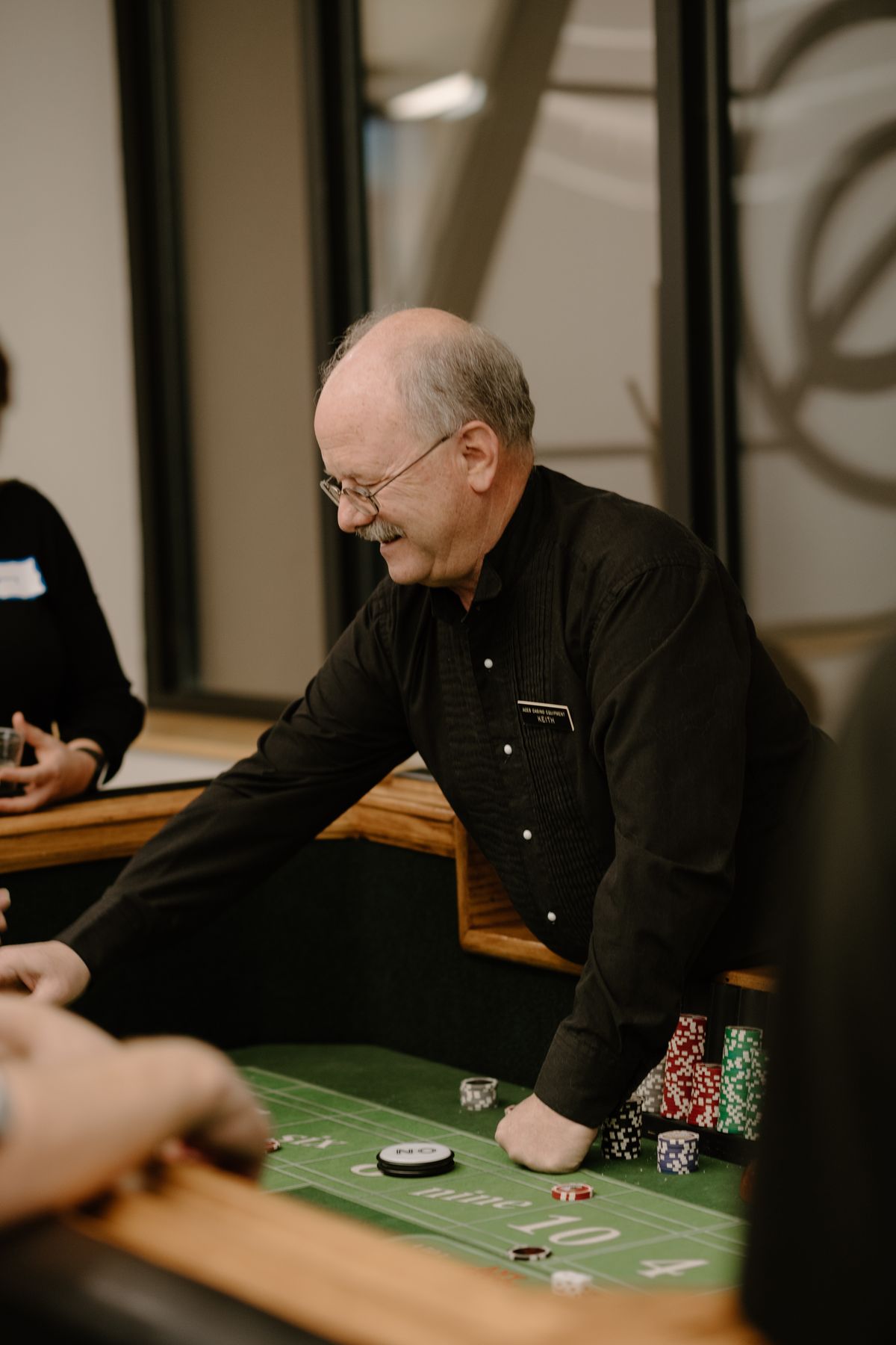 Smiling craps dealer running the table at K3 Casino Night