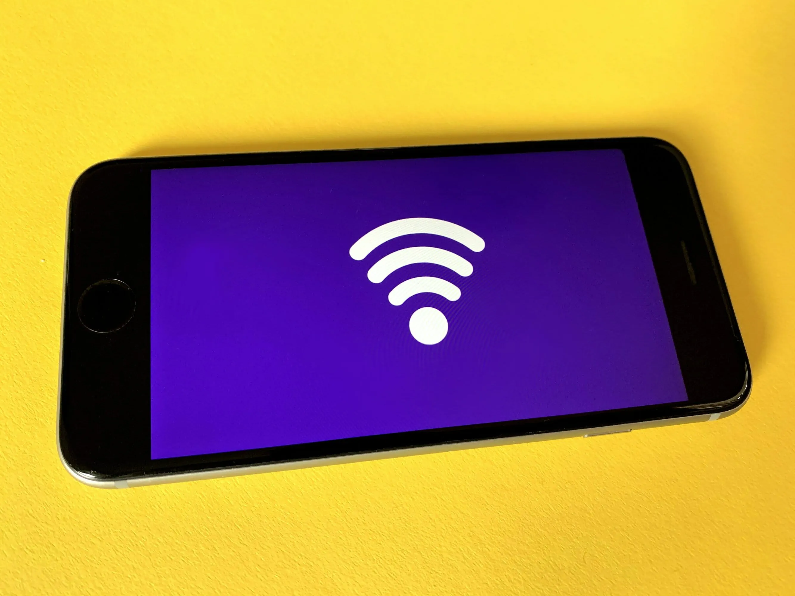Wireless technology symbol on purple screen.