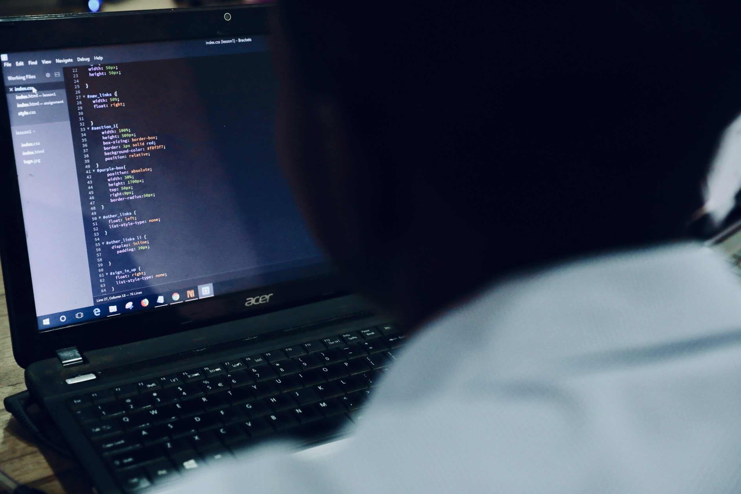 A man is coding on a laptop as a vCISO.