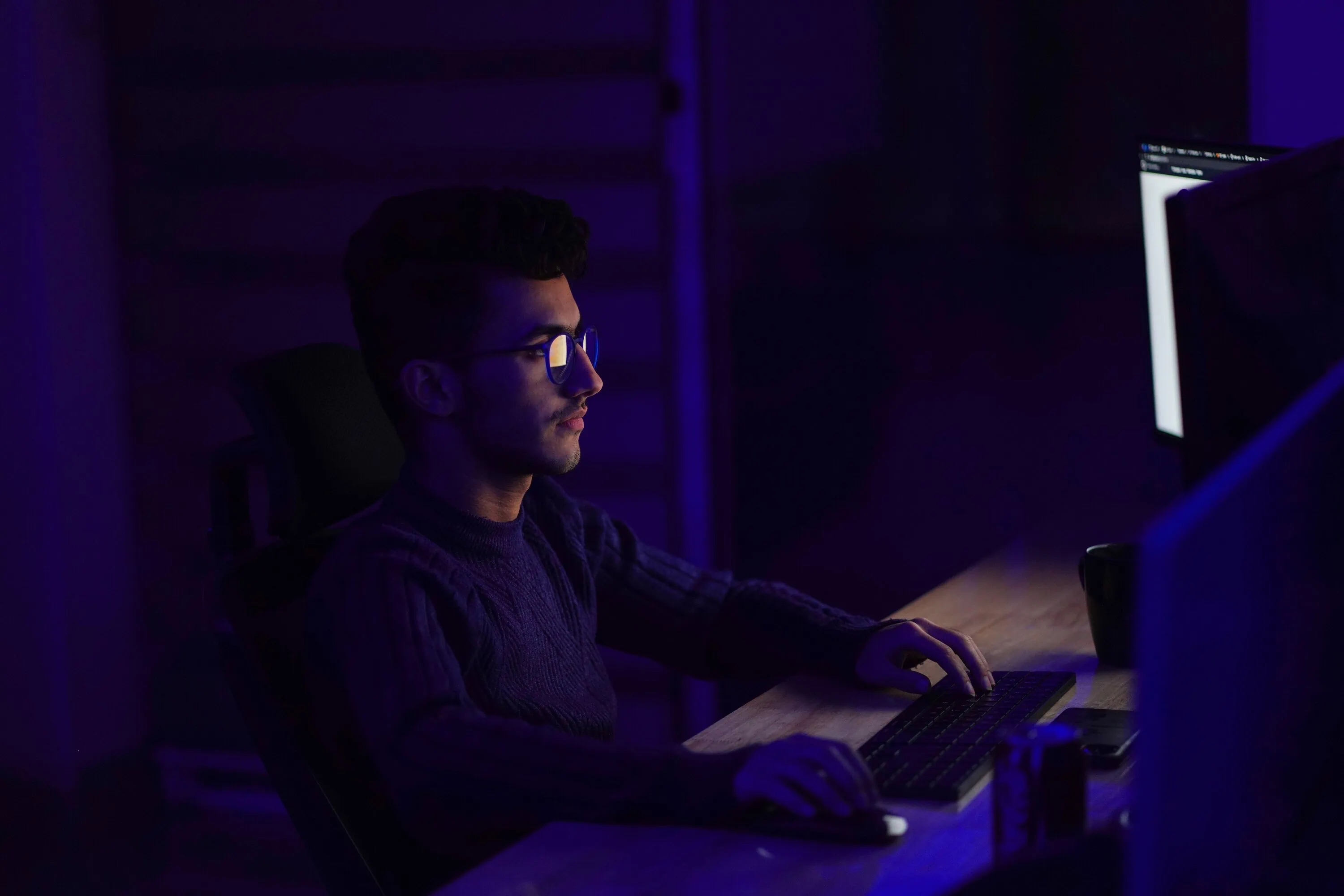 A vCISO working on a computer at night.