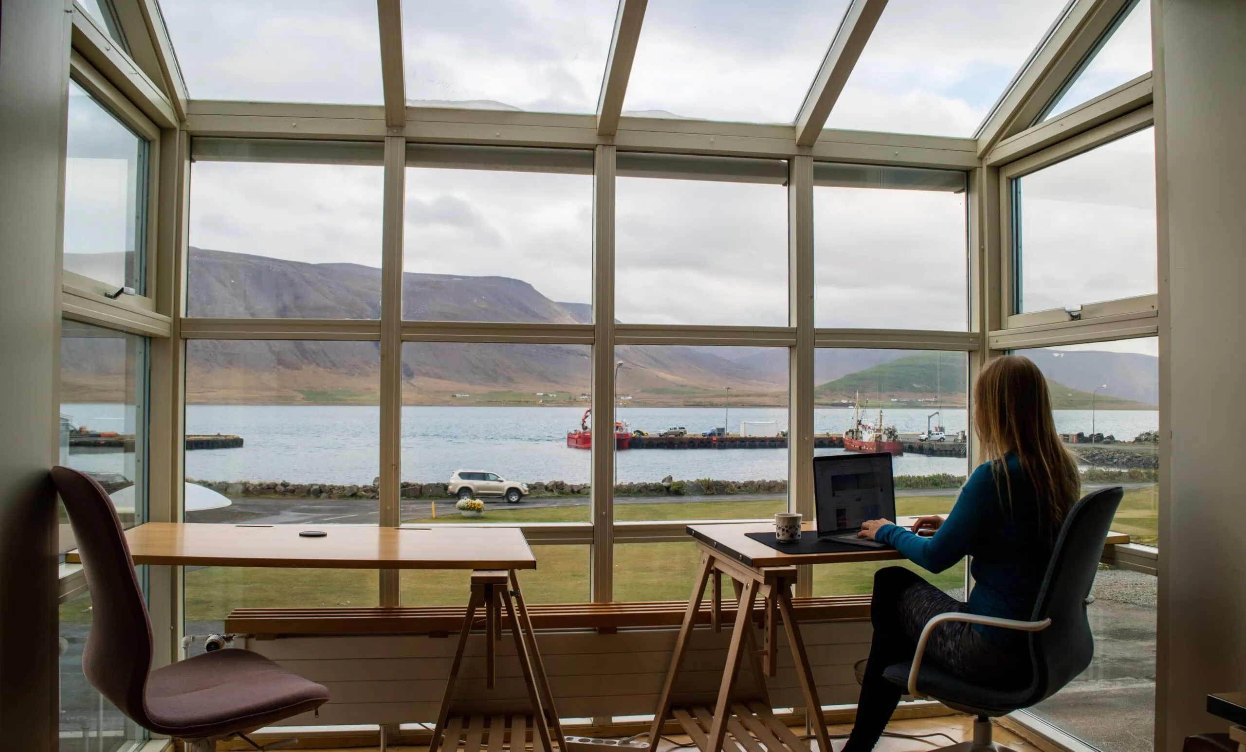 A woman manages IT services at a desk with a large window view.