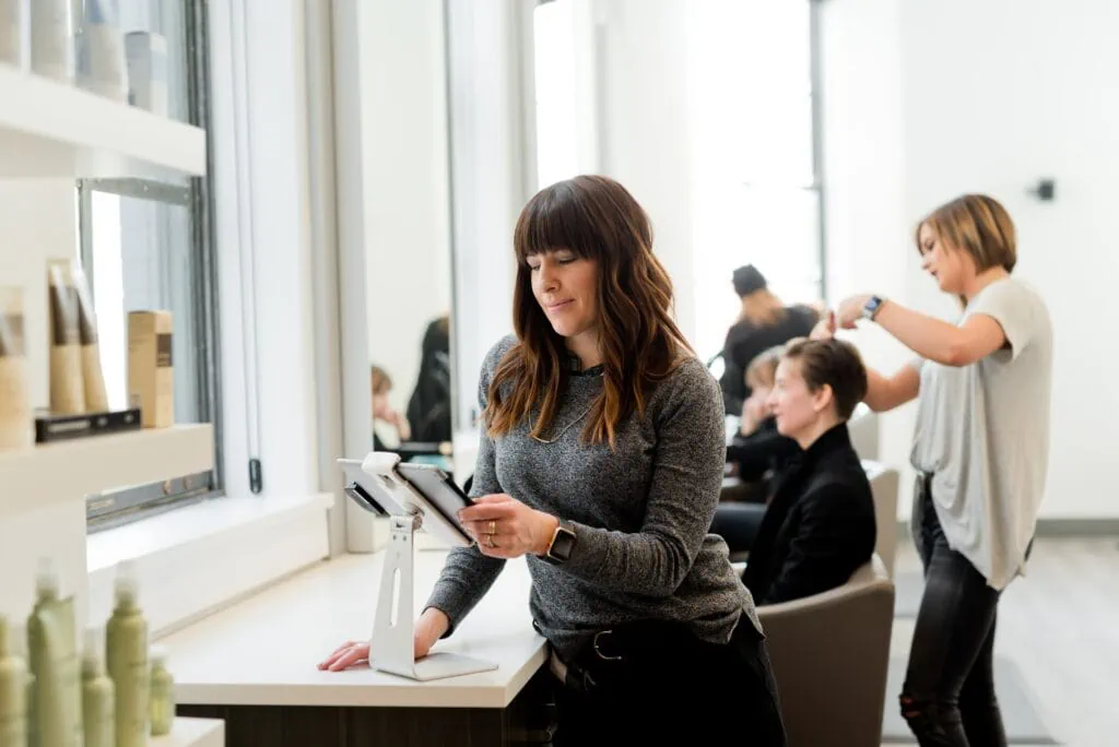 A woman utilizing Small business IT solutions in a hair salon through a tablet.