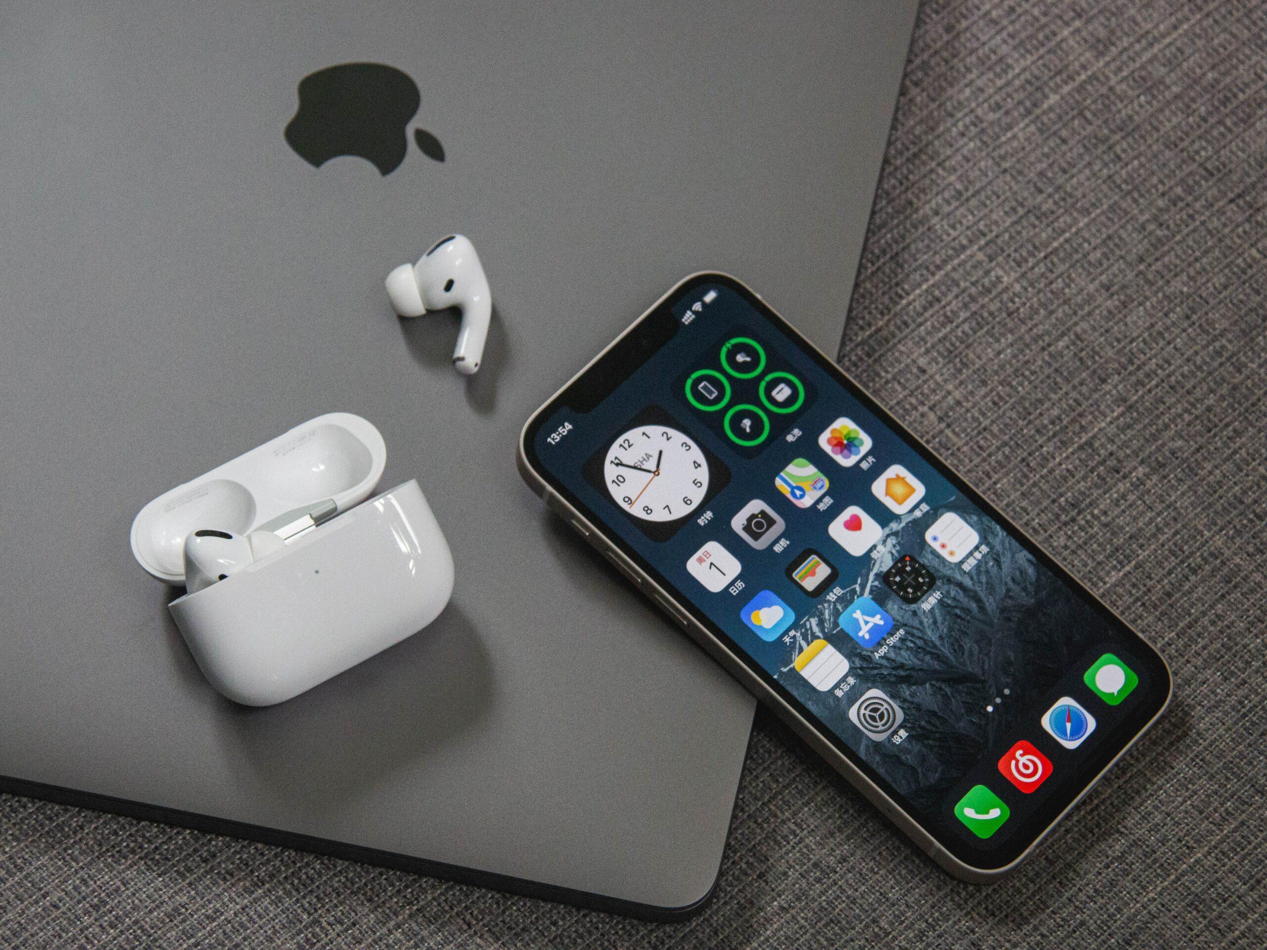 An Apple AirPods is sitting next to a laptop, demonstrating the setup of email on an Apple iPhone.