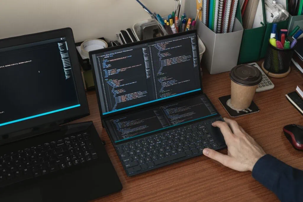A man is working on a laptop, managing code developed by DevOps team.