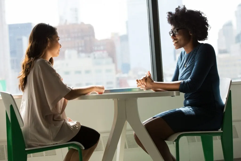 Two women discussing DevOps strategies at a table in an office.