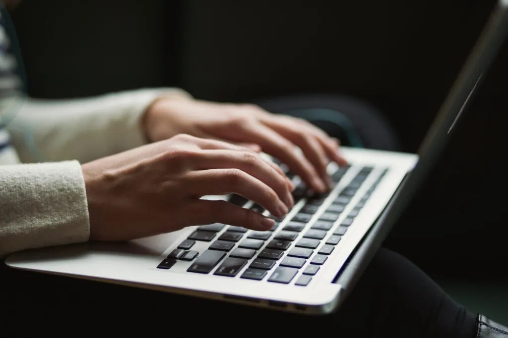 A woman's hands securely typing on a laptop, providing Cybersecurity as a Service.