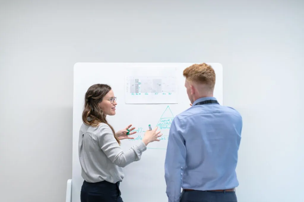 Two people standing in front of a whiteboard, discussing managed IT services for small businesses.