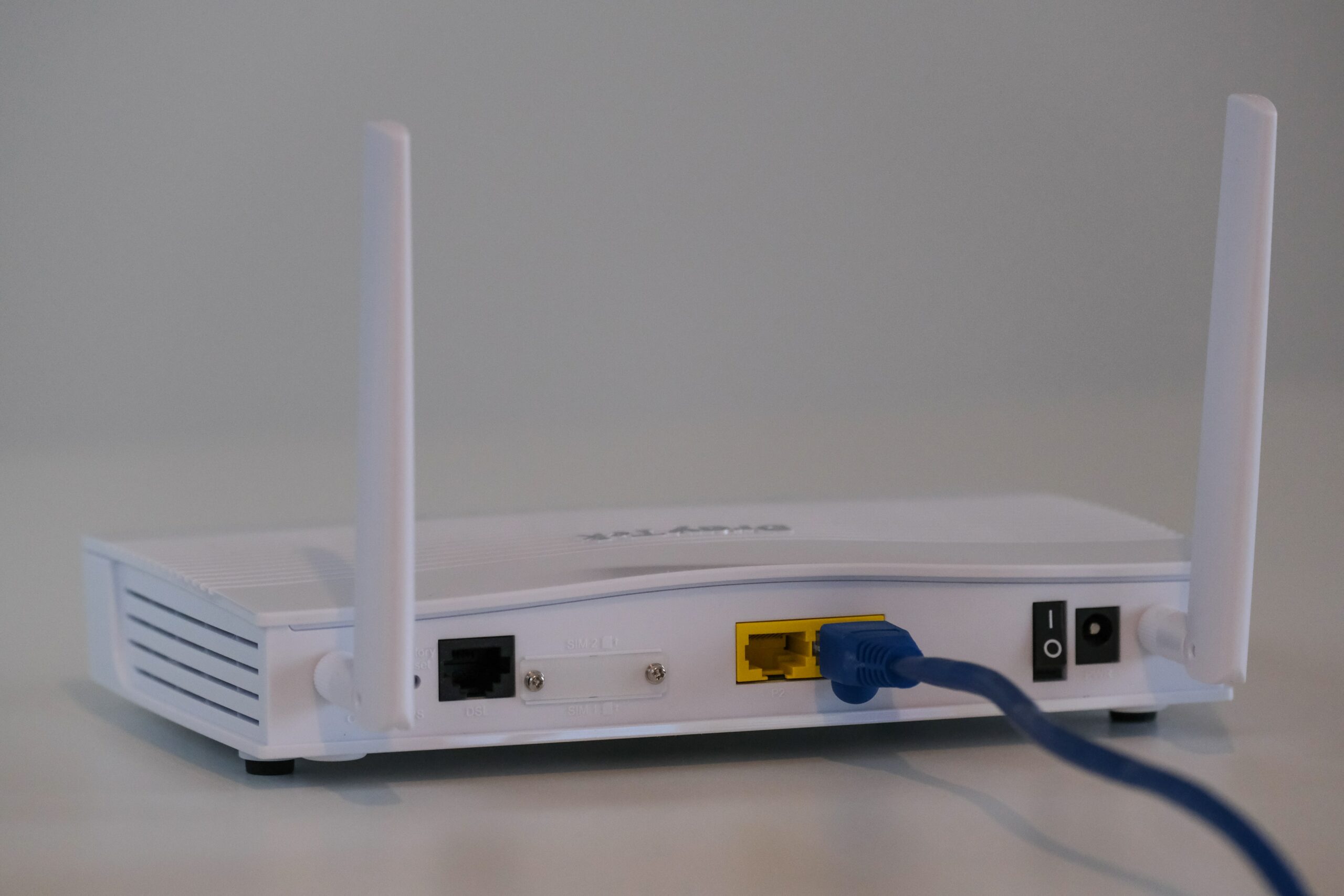 A white router with a blue cable attached to it for teleworking.