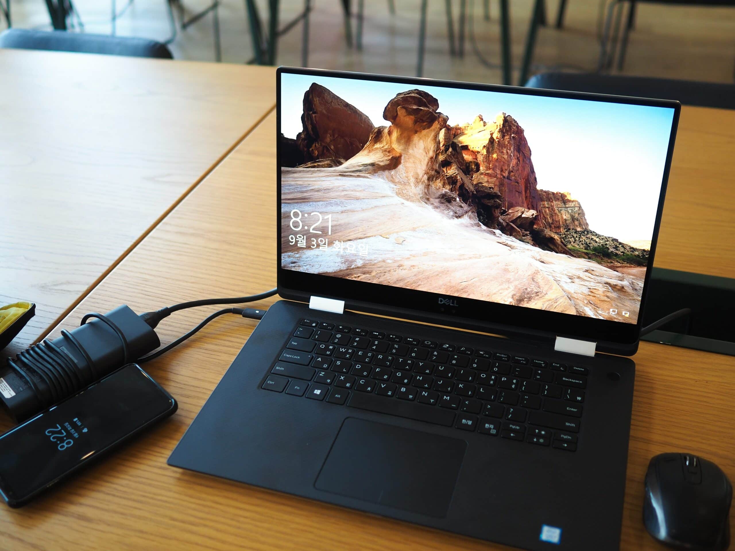 A Dell laptop is sitting on a table next to a charger after owner troubleshooted why it was running slow.