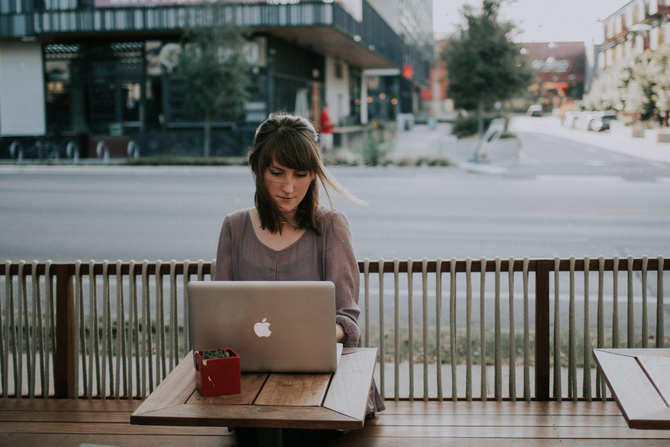 A woman sitting on a bench with a laptop, learning how to sync files with Google Drive.