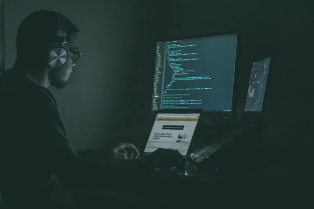 A man providing cybersecurity services for small businesses, sitting in front of a computer with code on the screen.