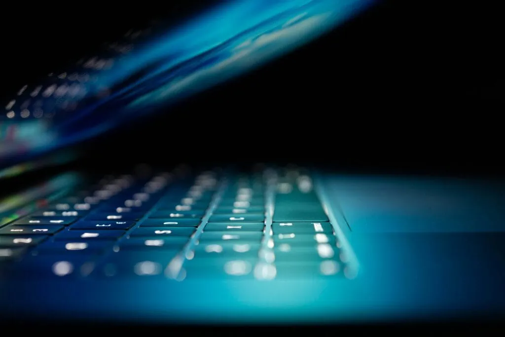 A close up of a laptop keyboard in the dark used by IT tech that provides business information security solutions.