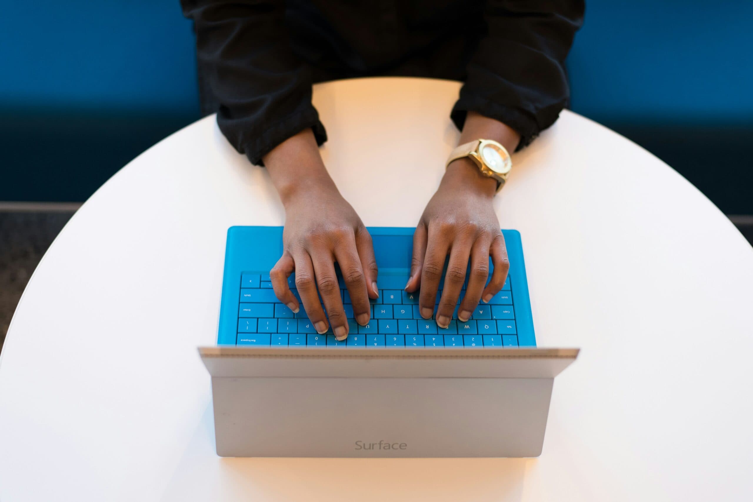 A woman's hands diligently typing on a blue surface laptop, researching, “how can I protect my privacy”.