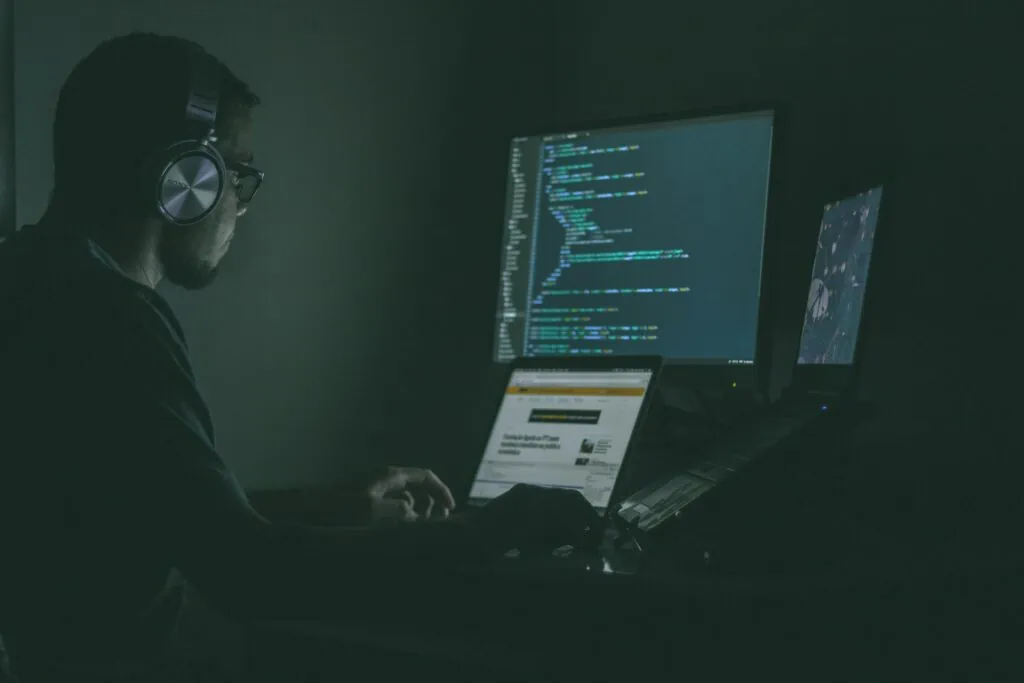A man wearing headphones and working on a computer, conducting cyber security Strategy.