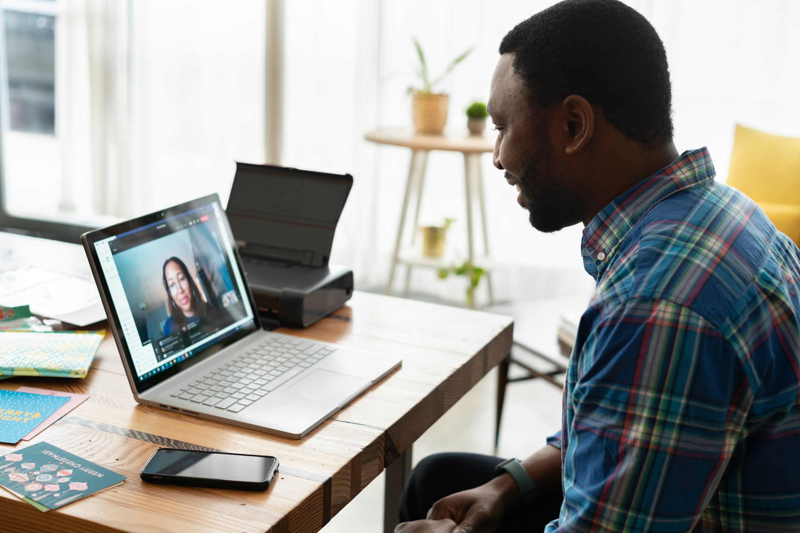 A man attending a video call with a woman on a laptop in an office setting to discuss managed services benefits.