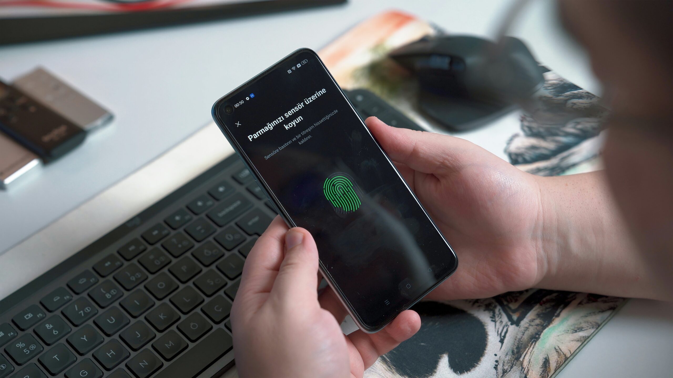A person holding a smartphone with a green fingerprint on it after enabling MFA due to reading about the top cyber security tips.