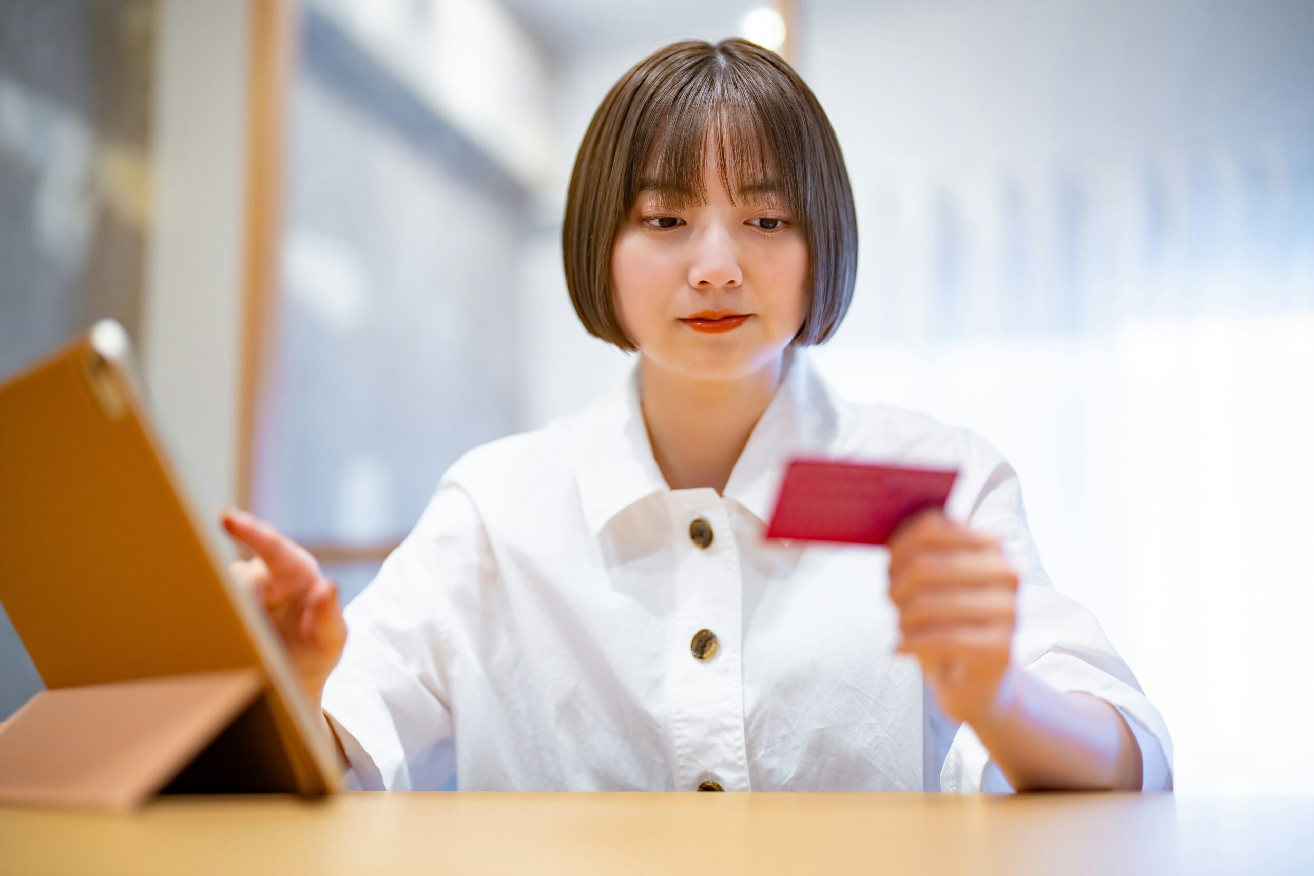A young woman holding a credit card in front of a laptop, learning how to protect personal information online while entering in information.