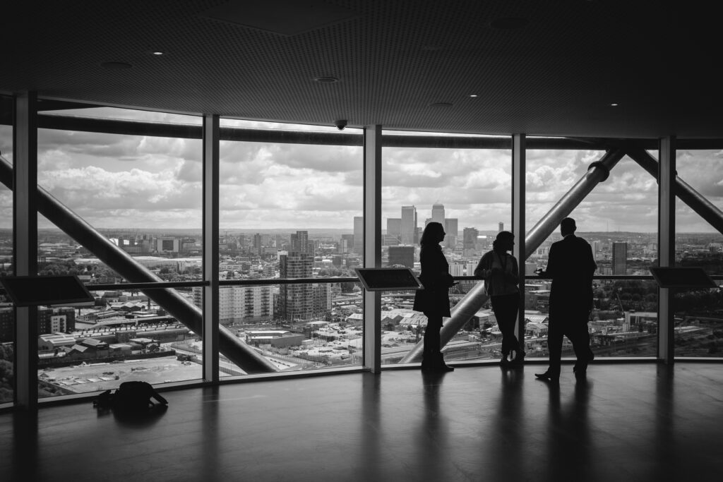 Silhouettes of people inside a room with large windows overlooking a cityscape after having discussed IT infrastructure management services.