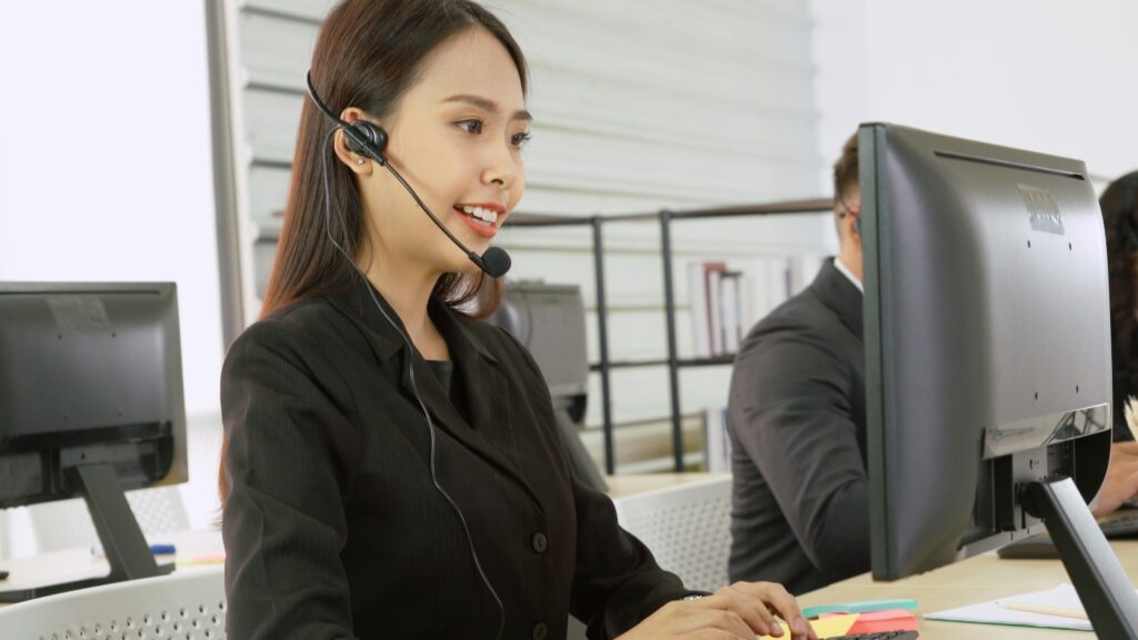 Representative of IT managed service provider with headset working at a computer.