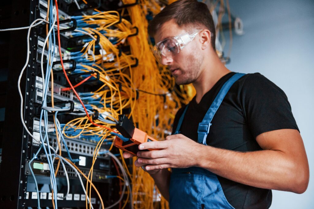 Technician using a testing device on a server in a data center as part of IT infrastructure management services.