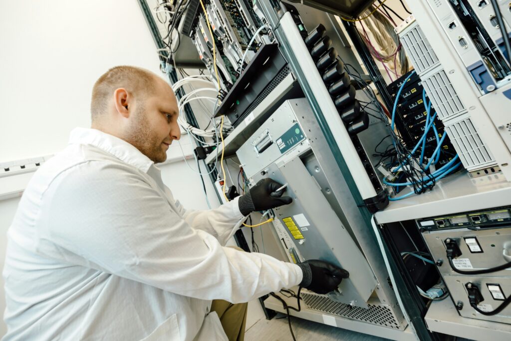 Technician fixing network equipment in a server room as part of IT infrastructure management services.