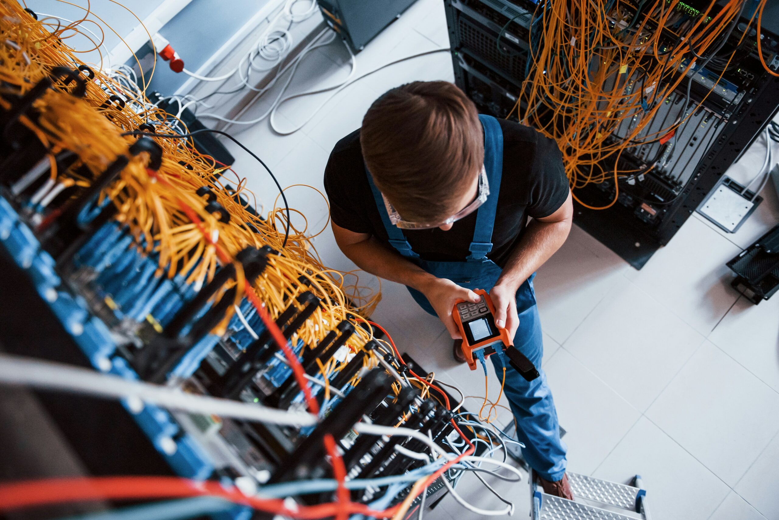 Technician using diagnostic equipment to troubleshoot network issues in a server room as part of managed services offered.