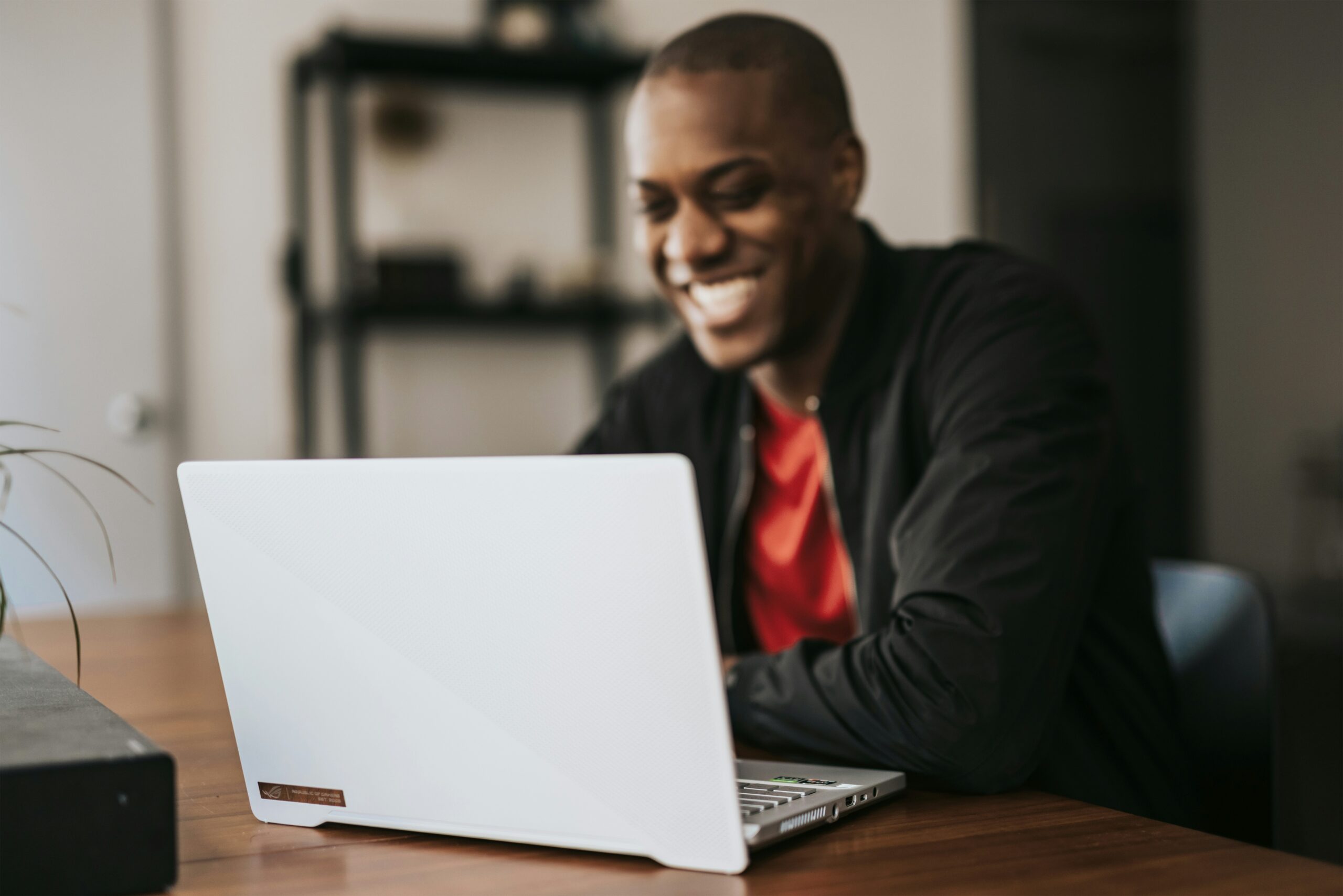 A smiling person working on a laptop at a desk, researching what are managed services for SMB.