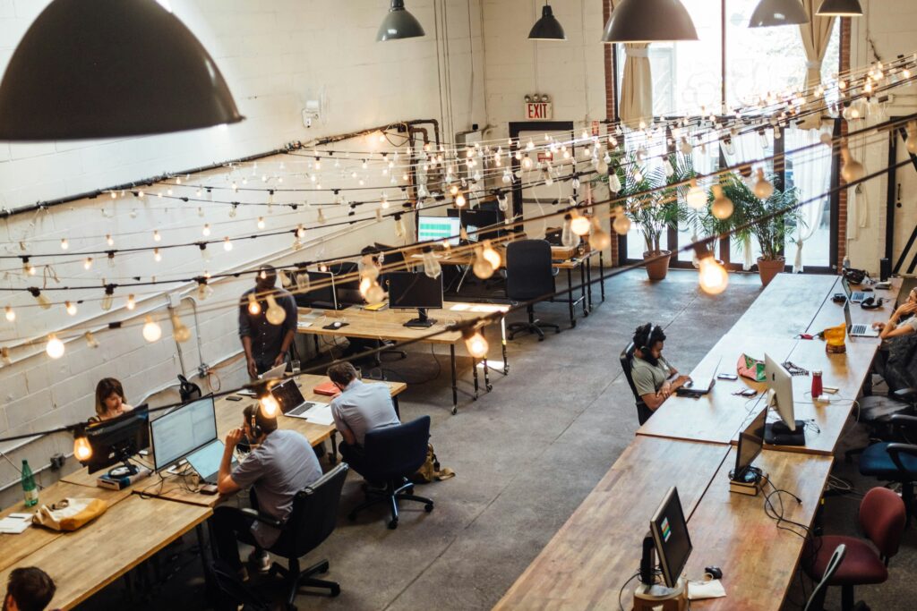 Modern office space with employees working at desks under decorative string lights, specializing in managed IT services for small businesses.