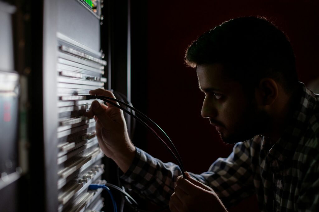 Man inspecting network cables in a dark server room, providing IT services for business.