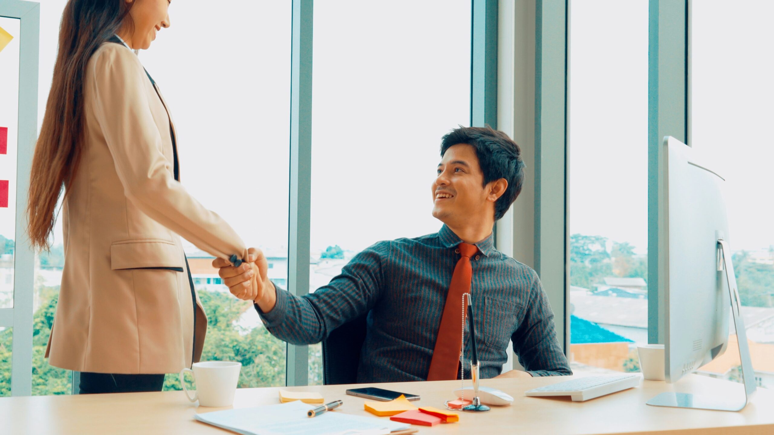 Two IT professionals shaking hands in an office setting after discussing responsibilities of managed service company.
